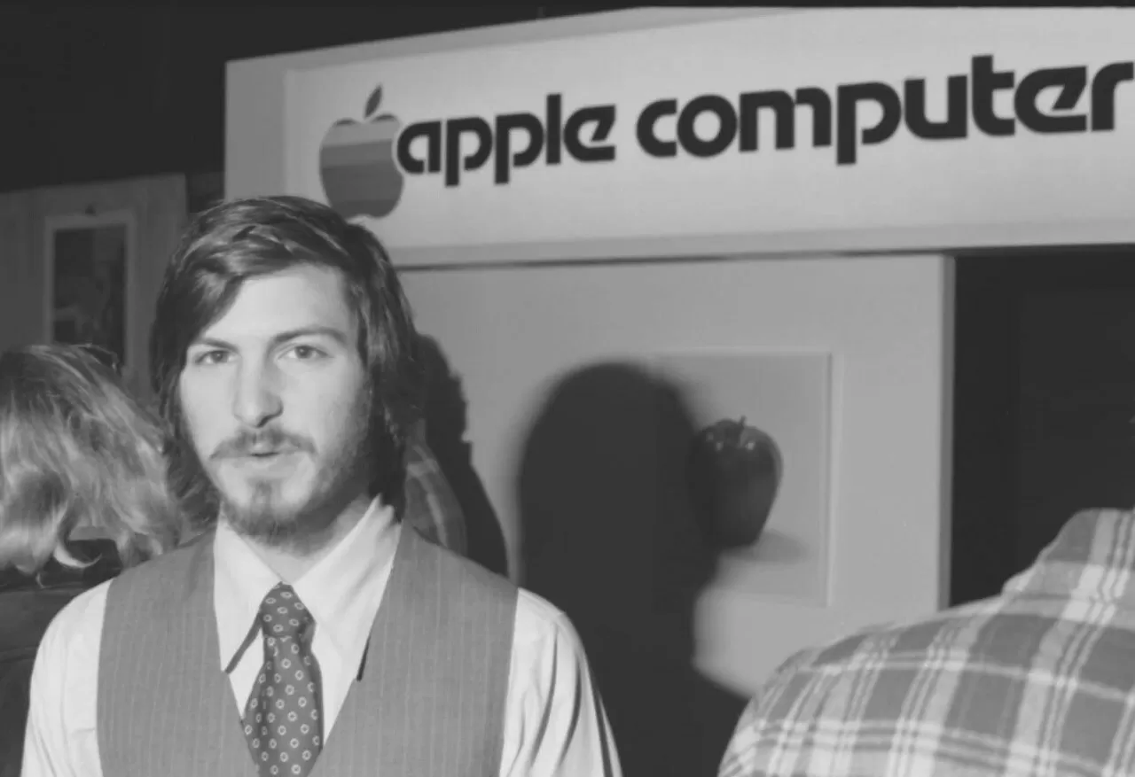 Steve Jobs standing beneath the first Apple Computer trade sign at a ca. 1976 trade show. The sign was later used for year to identify the company's offices in Cupertino, Ca. To be sold at auction on Jan. 27, 2023 img#1