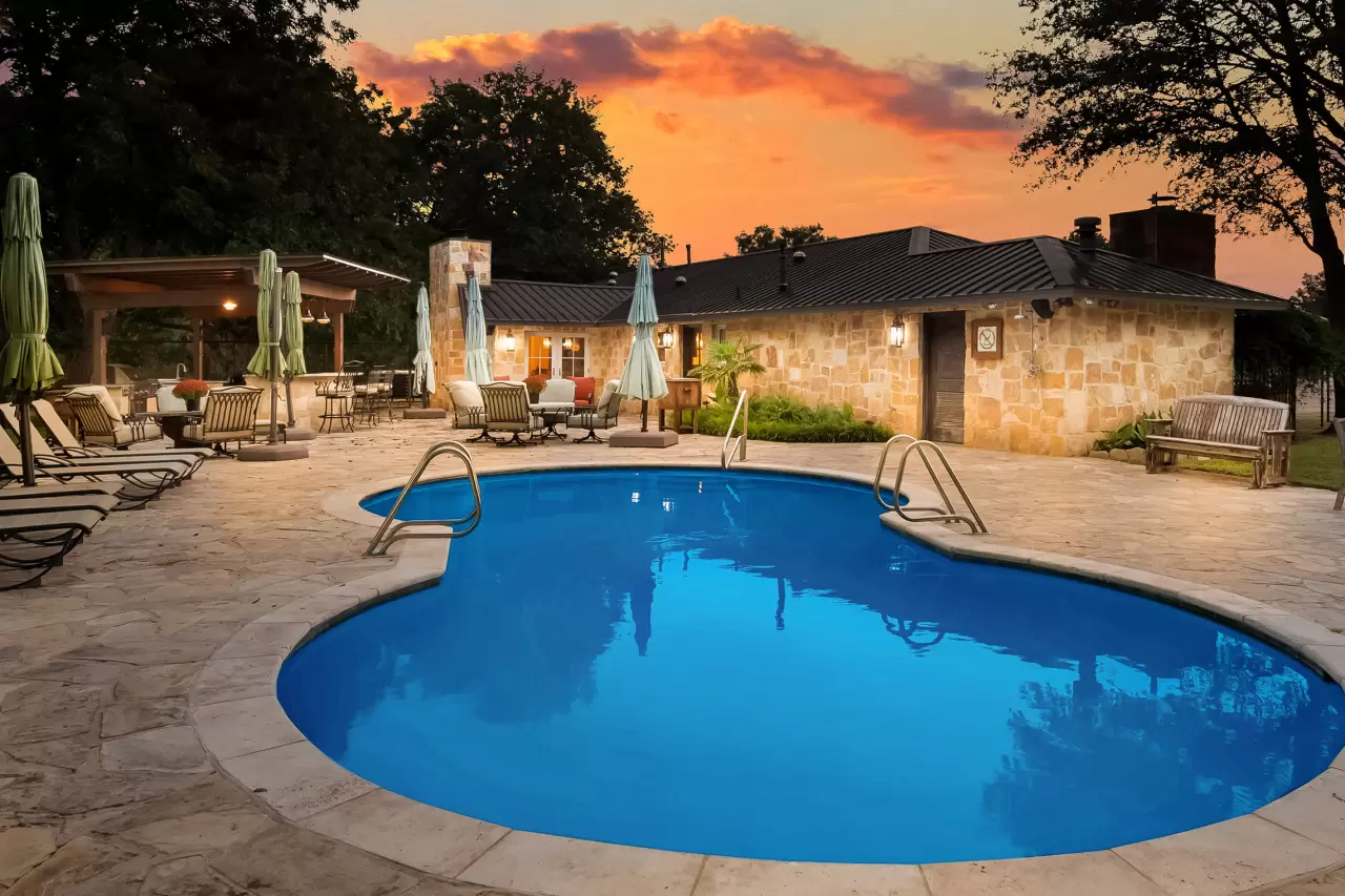 The outdoor living areas of the Creek House, the property’s other residence, feature a custom pool with a large, stone-paver surround, jacuzzi tub and covered summer kitchen with countertop seating. img#2