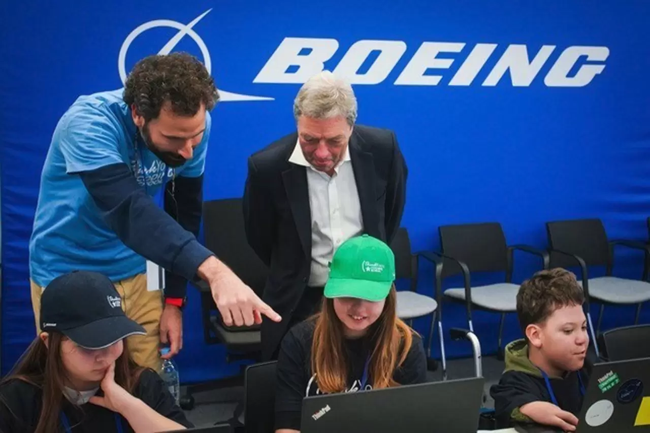 A ThinkYoung instructor shows Boeing International President Sir Michael Arthur the coding school lesson as a young student works. (Boeing photo) img#1